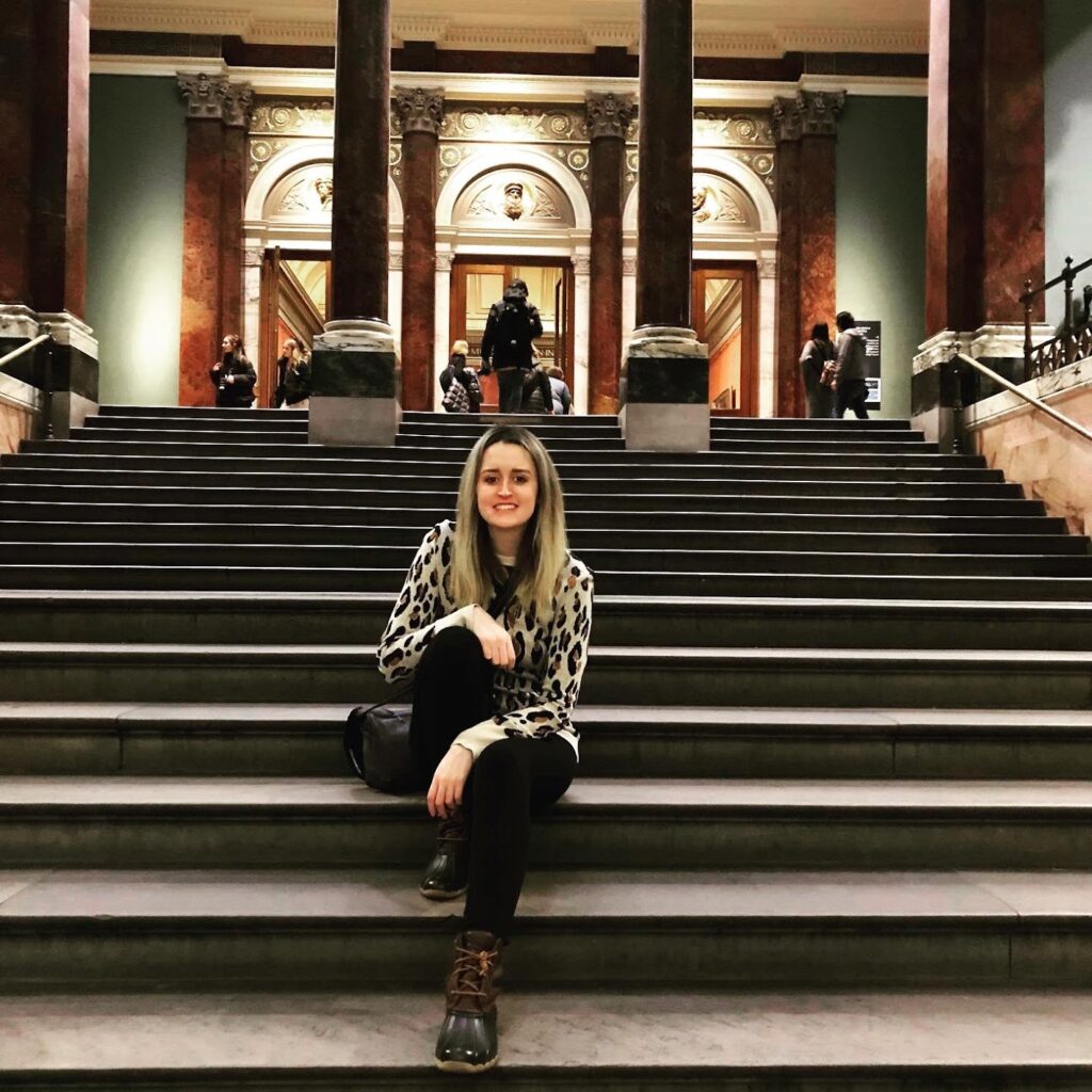 Katherine Beirne writer blonde young woman on a staircase in front of a building