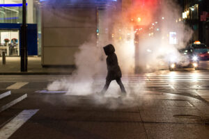 Silhouette walking across steamy city street