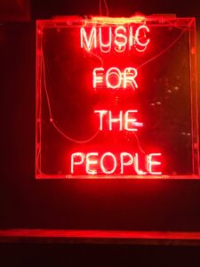 Red neon sign that says music for the people