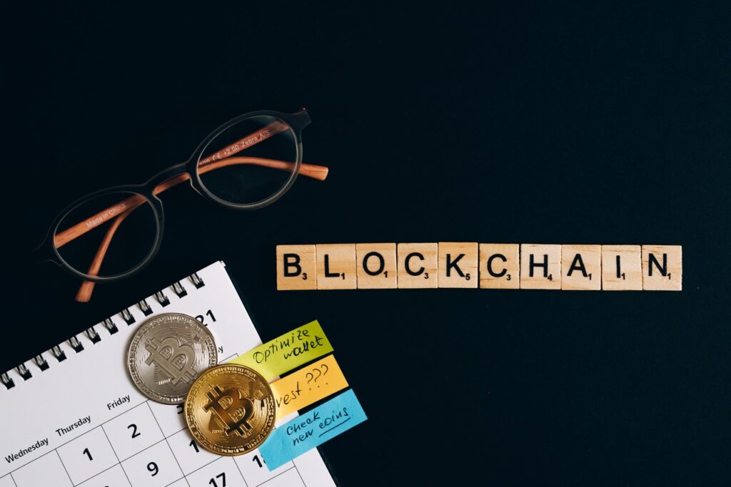 Image of a desk with scrabble letter arrnged to spell out blockchain and a picture of a bitcoin on a calender image by Olya Kobruseva at Pexels